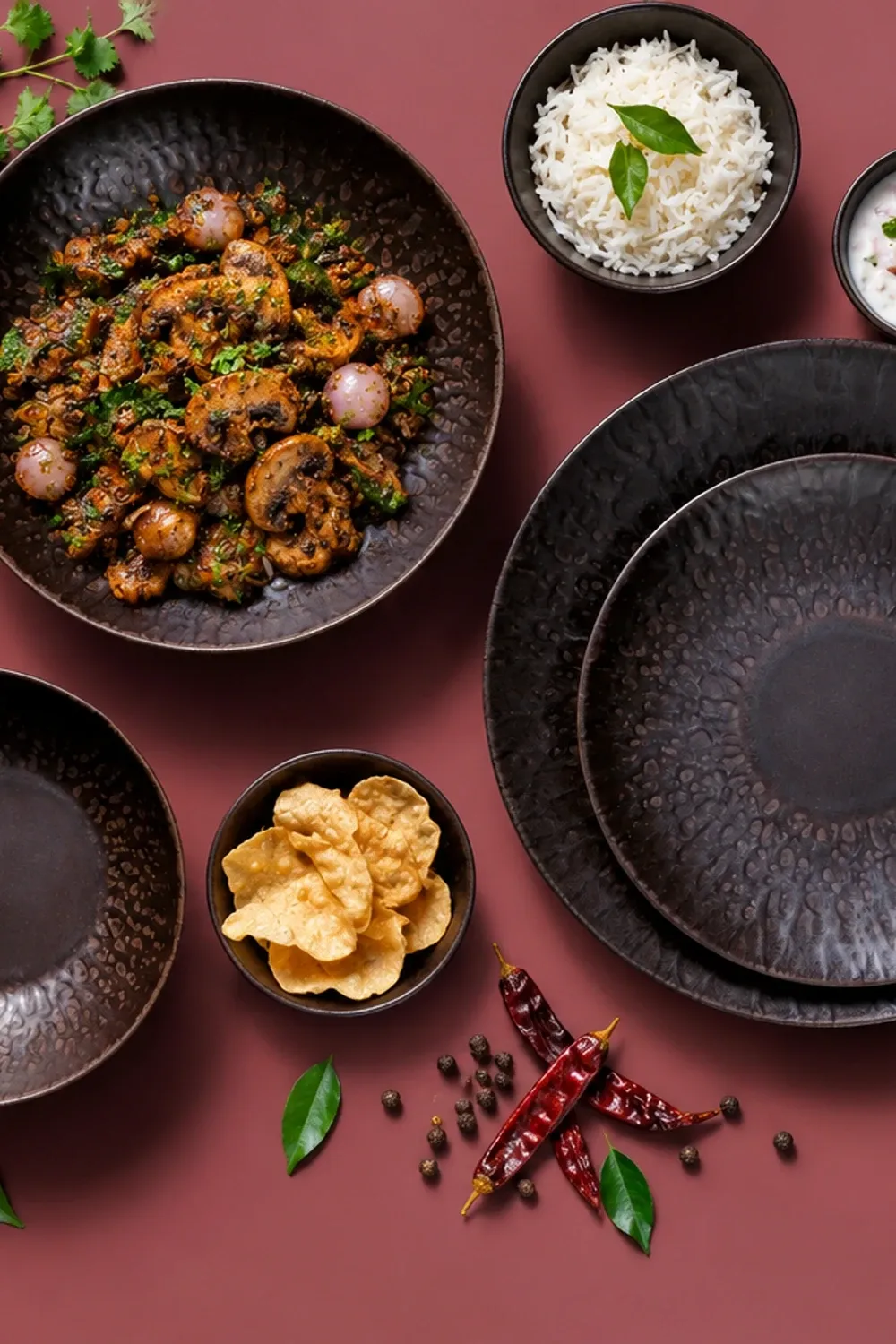 Ruston dinnerware arranged with Chettinad mushroom pepper fry with pearl onions and curry leaves.